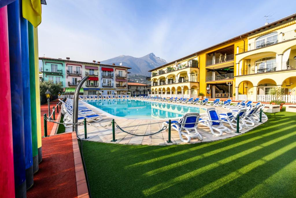 a large swimming pool with blue chairs next to buildings at Giardino dei Colori 107 - Residence Pool&Fitness in Toscolano Maderno