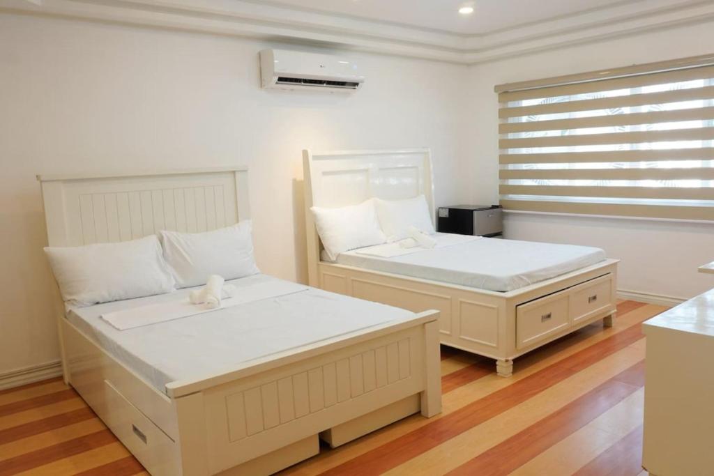 1 Schlafzimmer mit 2 Betten und einem Fenster in der Unterkunft Makati Altean Apartment (Leonora Room) in Manila