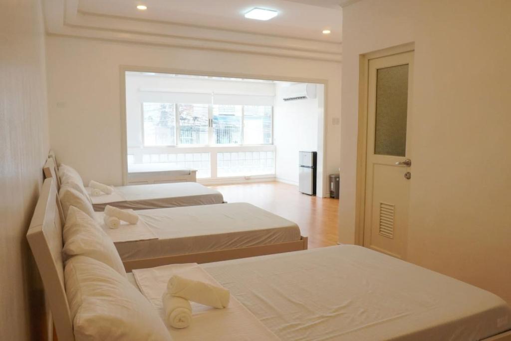 una stanza con tre letti e una finestra di Makati Altean Apartment (Maura Room) a Manila