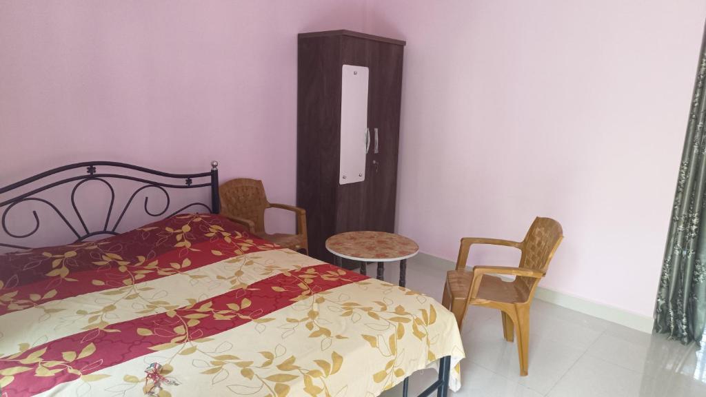 - une chambre avec un lit, deux chaises et une table dans l'établissement Makayla Farm Stay, à Pernem