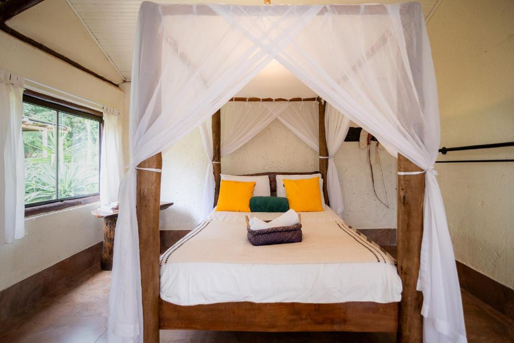 a bedroom with a canopy bed with yellow and orange pillows at Ecovila Coração da Mata in Brumadinho