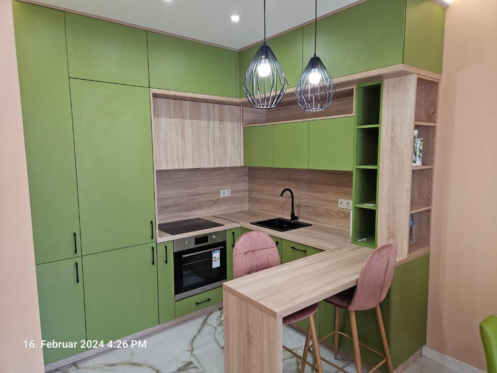 eine Küche mit grünen Schränken sowie einem Tisch und Stühlen in der Unterkunft Dilyanka in Pernik