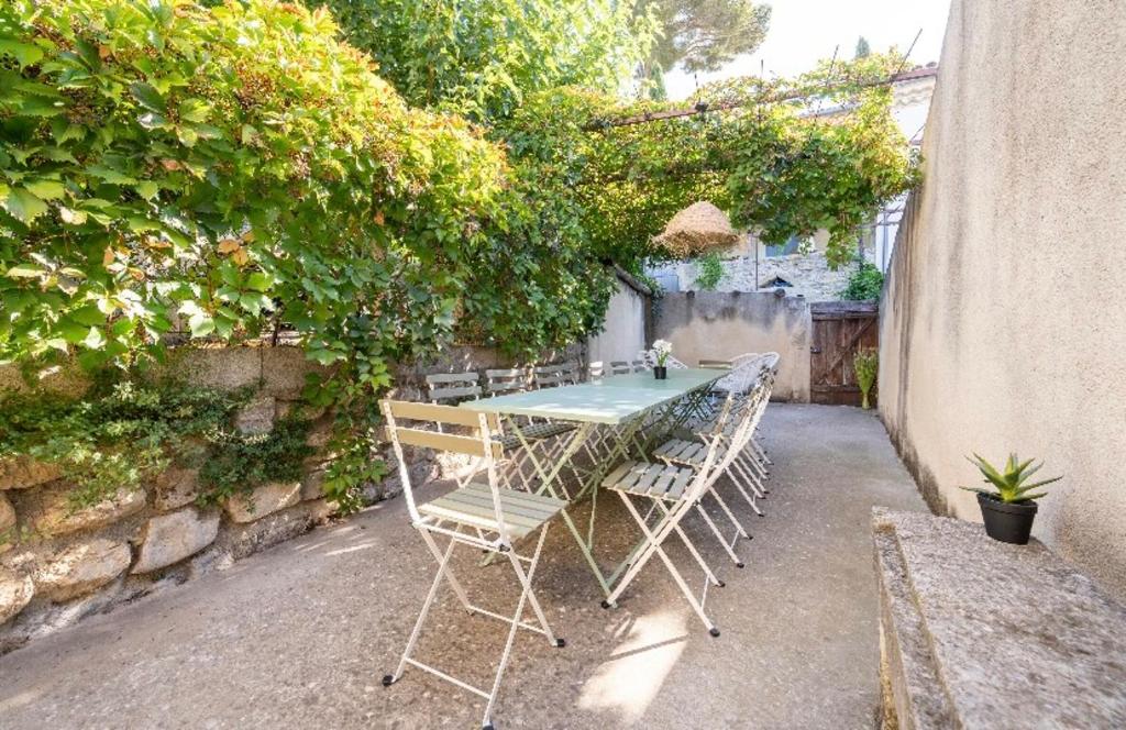 une table et des chaises assises sous une haie dans l'établissement Maison authentique à Montfrin avec terrasse, Air conditionné., à Montfrin