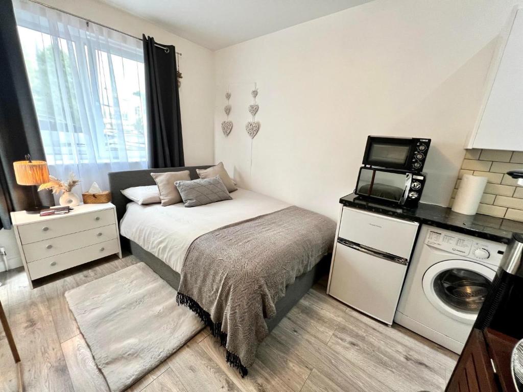 1 dormitorio pequeño con 1 cama y lavadora en Cosy Studio Flat, en Hither Green