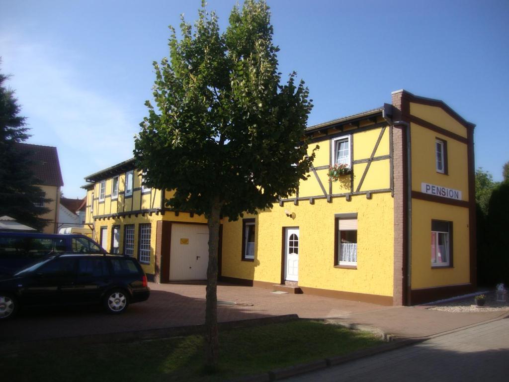 um edifício amarelo com uma árvore em frente em Pension & Ferienwohnungen Richter em Gerwisch
