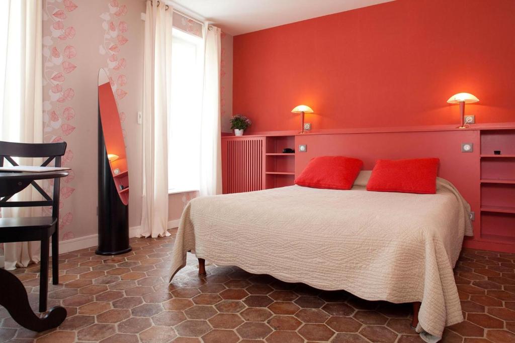 sypialnia z czerwonymi ścianami i łóżkiem z czerwonymi poduszkami w obiekcie Hotel du Saumon, Verneuil sur Avre w mieście Verneuil d’Avre et d’Iton