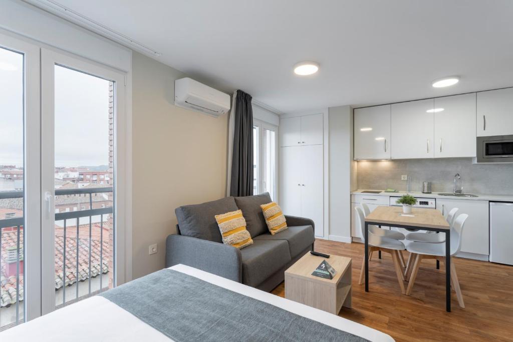 a bedroom with a bed and a couch and a kitchen at InsideHome Palencia Catedral in Palencia