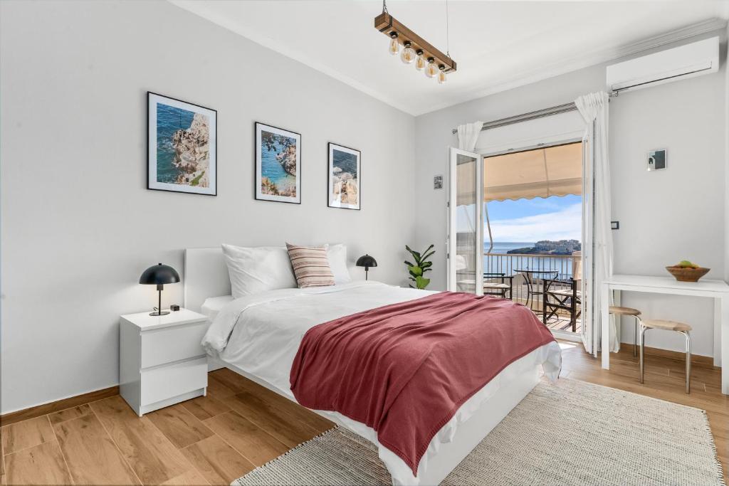 a white bedroom with a bed and a balcony at On The Port: Studio in Rafina
