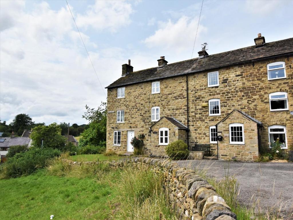 an old stone house with a stone wall at 2 Bed in Eyam PK812 in Eyam