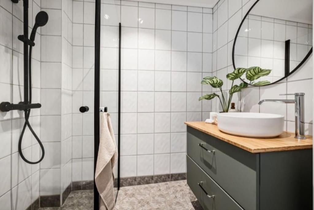 a bathroom with a sink and a shower with a mirror at Flott sentral 3 roms leilighet in Bergen