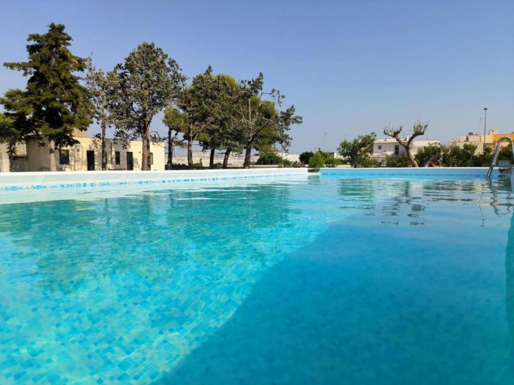 een groot zwembad met blauw water bij Borgo Borgia - Casa del Beccaio in Giurdignano