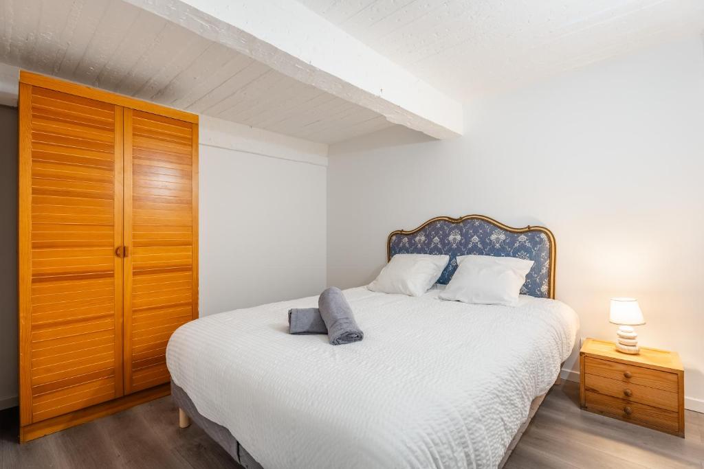 - une chambre avec un lit blanc et une armoire en bois dans l'établissement Central, 2 chambres, charmant., à Marseille