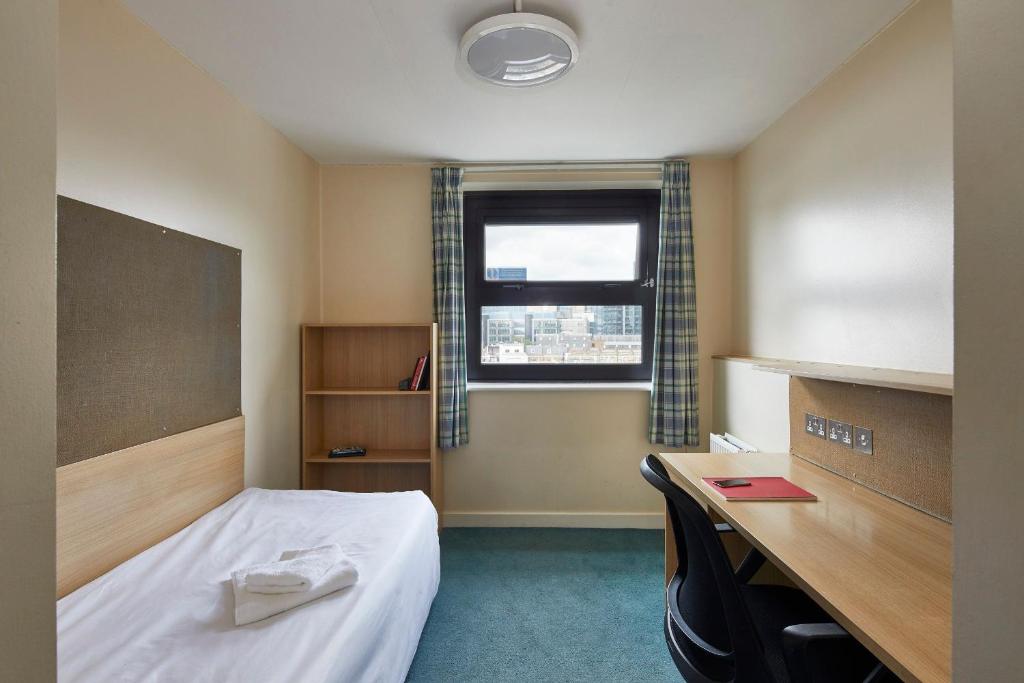 a room with a bed and a desk and a window at Ian Baker House in London