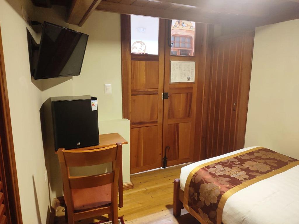 1 dormitorio con 1 cama y escritorio con TV en Magdalena Hotel & Suites en Cuenca