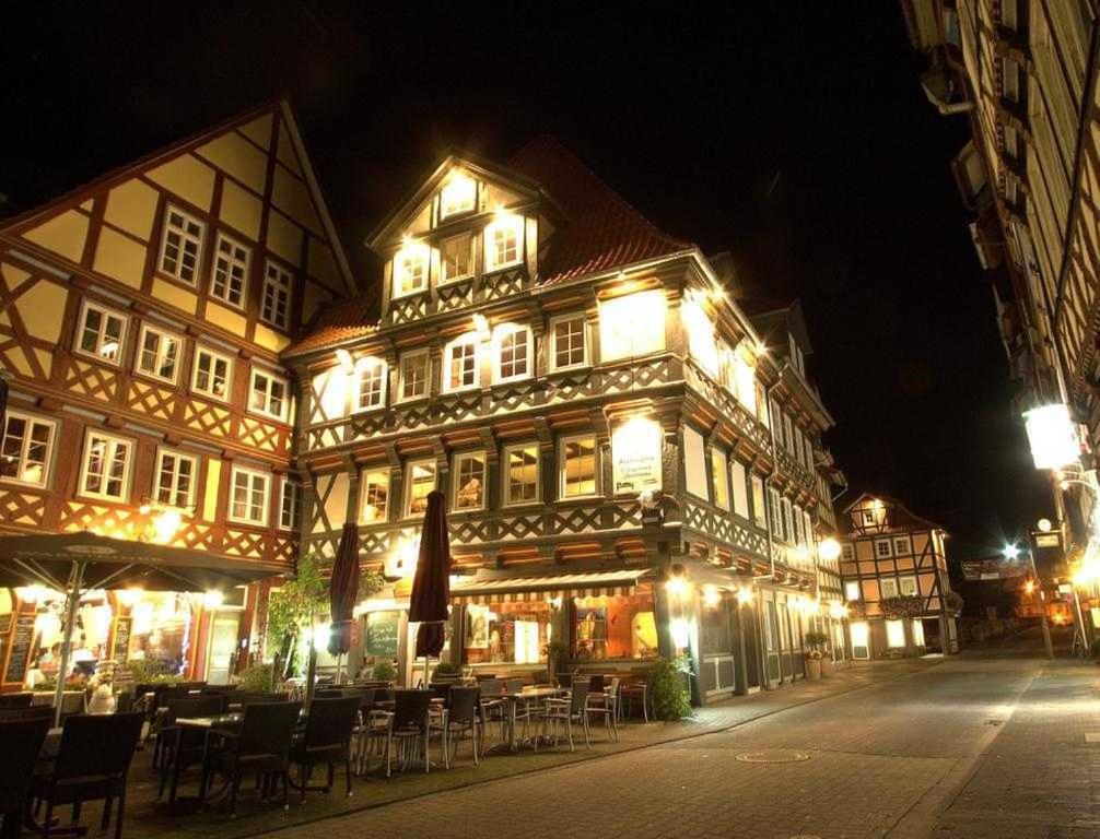 a lit up building with tables and chairs at night at Fachwerk-Hotel Eisenbart in Hannoversch Münden