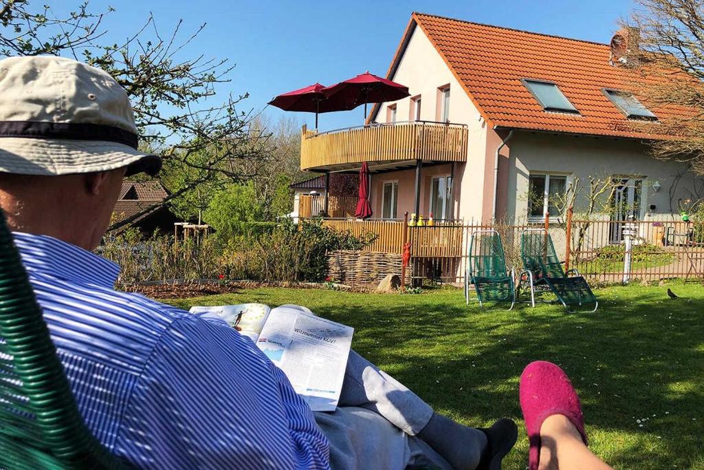 Ein Mann, der auf einem Gartenstuhl sitzt und ein Buch liest. in der Unterkunft Annehill Ferienwohnungen am Wittenborn in Hannoversch Münden