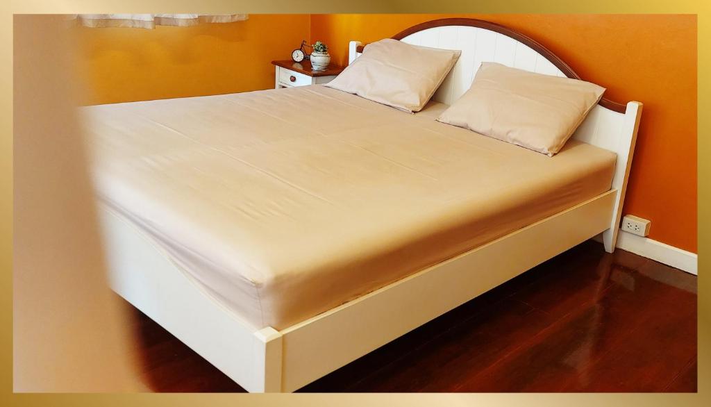 een groot bed met een wit bedframe in een kamer bij Sweetheart Tree Homestay in Bangkok
