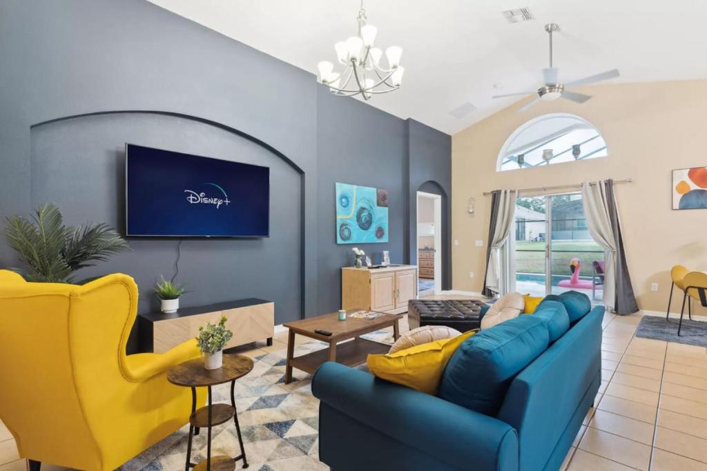 a living room with a blue couch and yellow chairs at Florida Pool House in Davenport