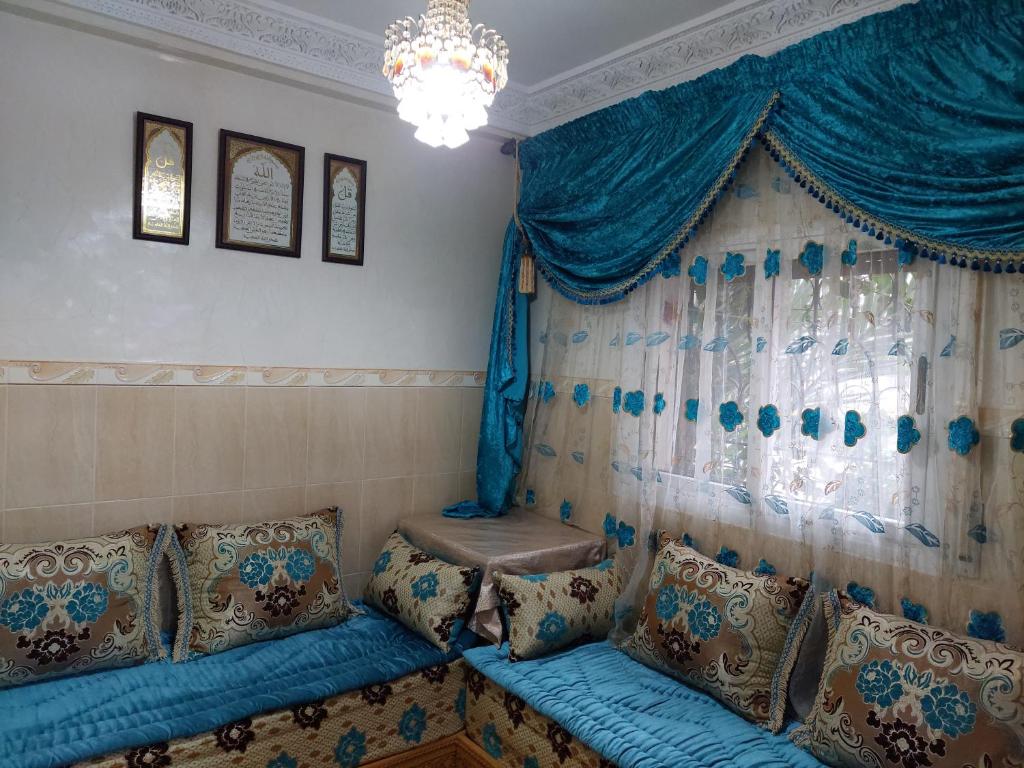 um quarto com um sofá azul com almofadas e uma janela em Apartamento con wifi em Nador