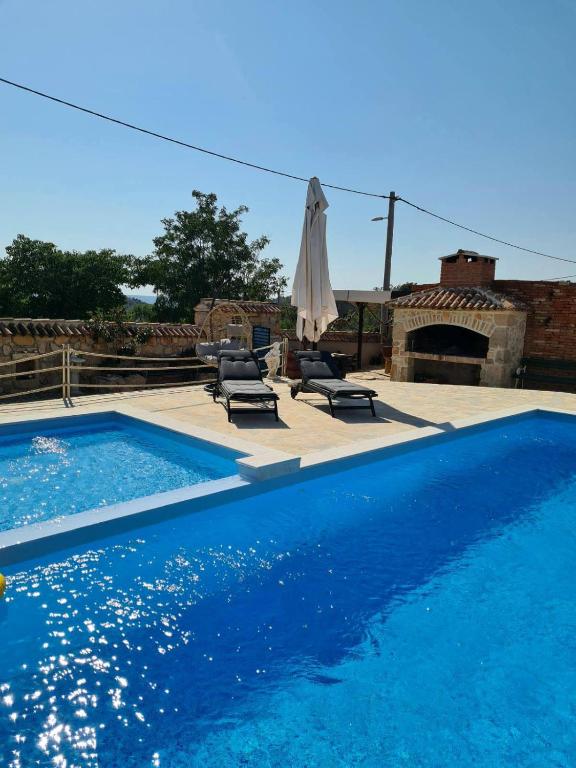 a swimming pool with chairs and an umbrella next to it at VILLA KUNTA in Donja Jagodnja