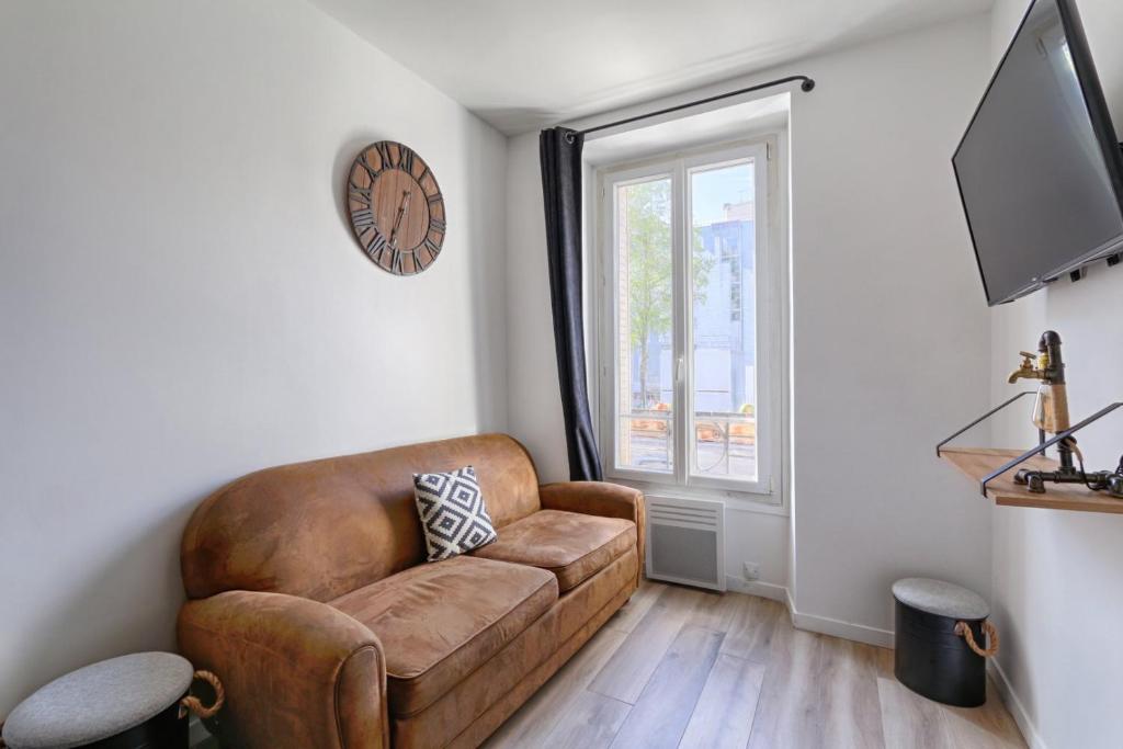 ein Wohnzimmer mit einem braunen Sofa und einem Fenster in der Unterkunft Magnifique appartement Porte d'Orléans in Montrouge
