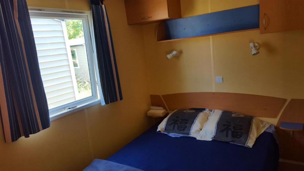 a small bedroom with a bed and a window at Mobilhome Clermont Auvergne Climatisé in Sigean