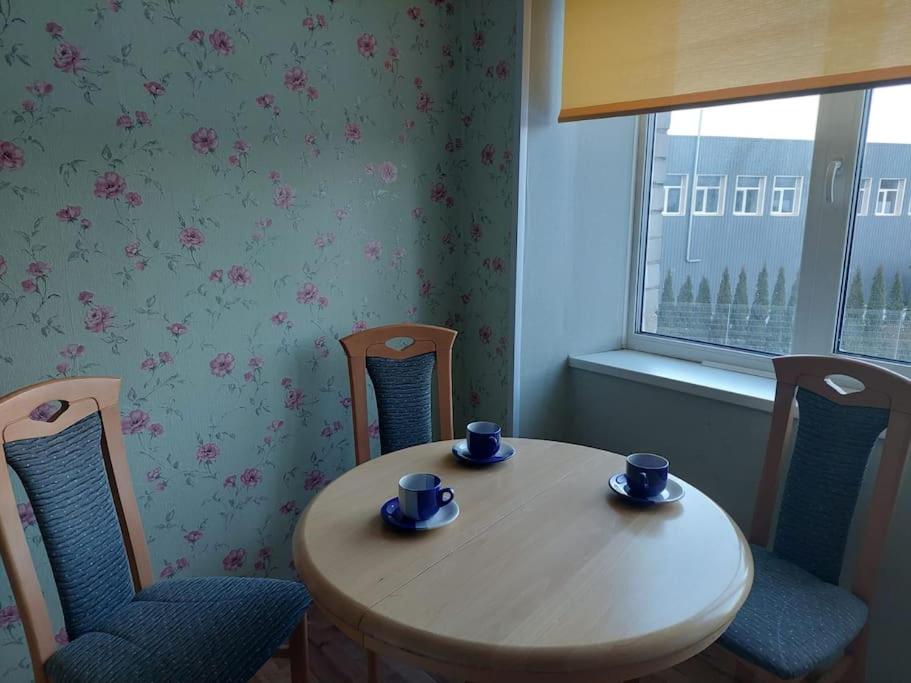 a table and chairs with cups and saucers on it at Apartamenti dzīvoklis Ogre. in Ogre