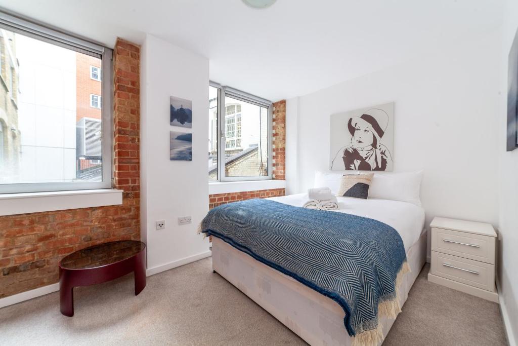 1 dormitorio con cama y pared de ladrillo en Elegance & Chic Design - 2-bedroom Haven, en Londres
