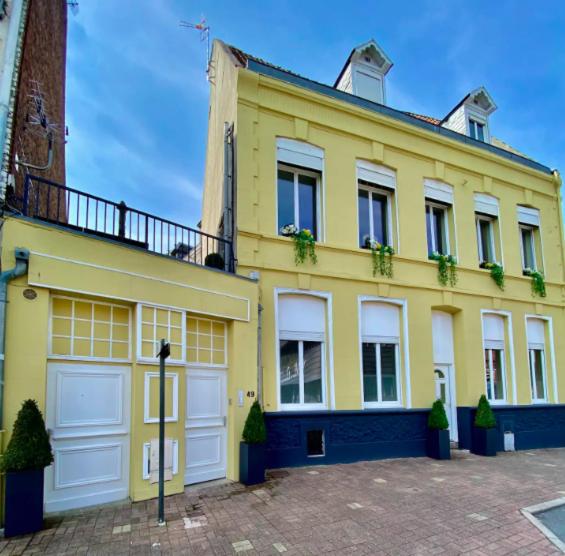 une maison jaune avec des portes de garage blanches dans un parking dans l'établissement N3 Le Colvert - La Maison Sévigné Appart Hôtel, à Béthune