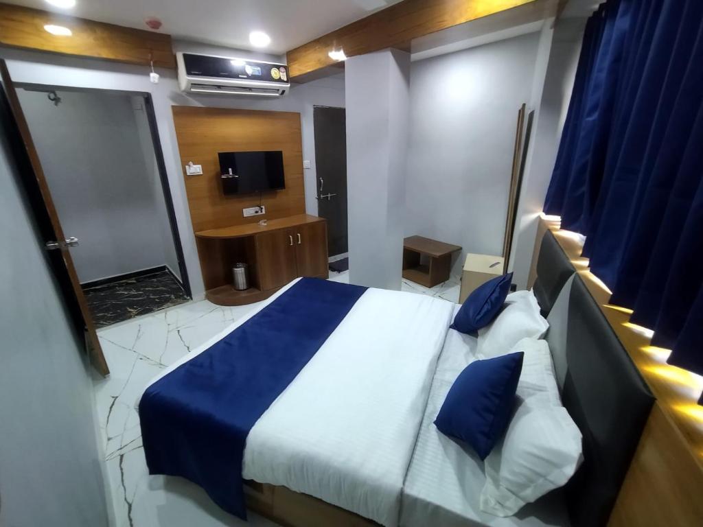 una camera con letto e un bagno con televisore di HOTEL SHREE RADHE a Ahmedabad