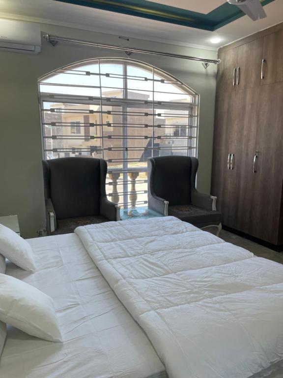 - une chambre avec un grand lit blanc et deux chaises dans l'établissement BAHRIA HOLLIDAY HOME 2, à Rawalpindi