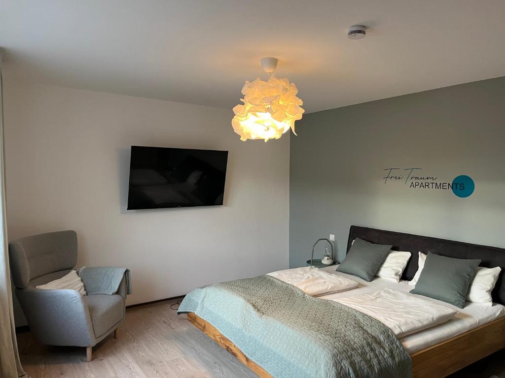 a bedroom with a bed and a chair and a chandelier at FreiTraum Apartments No1 im Zentrum von Bad Neustadt in Bad Neustadt an der Saale