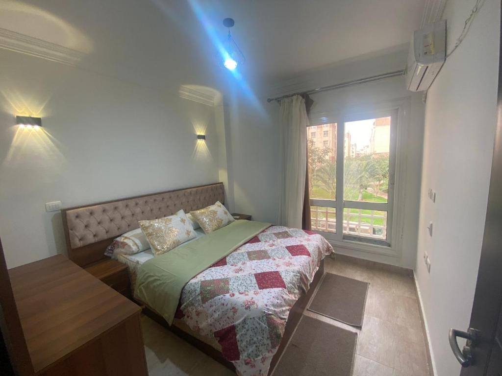 a small bedroom with a bed and a window at Luxurious, fully furnished and well equipped apartment with modern amenities, stunning views, and convenient location for remote work or studying from home in Madinaty