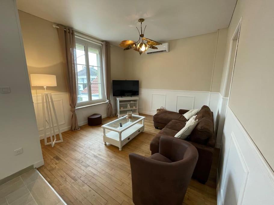 ein Wohnzimmer mit einem Sofa und einem Tisch in der Unterkunft Charmante maison 2 chambres avec cour et jardin in Sainte-Savine