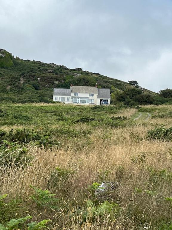 a house on top of a hill in a field at Pencaer Holiday Cottage in Goodwick