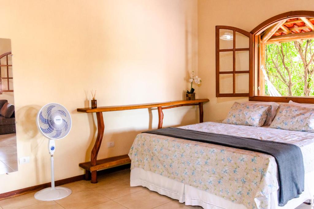 a bedroom with a bed with a fan and a window at Kefi Chalés - Vale do Capão in Palmeiras