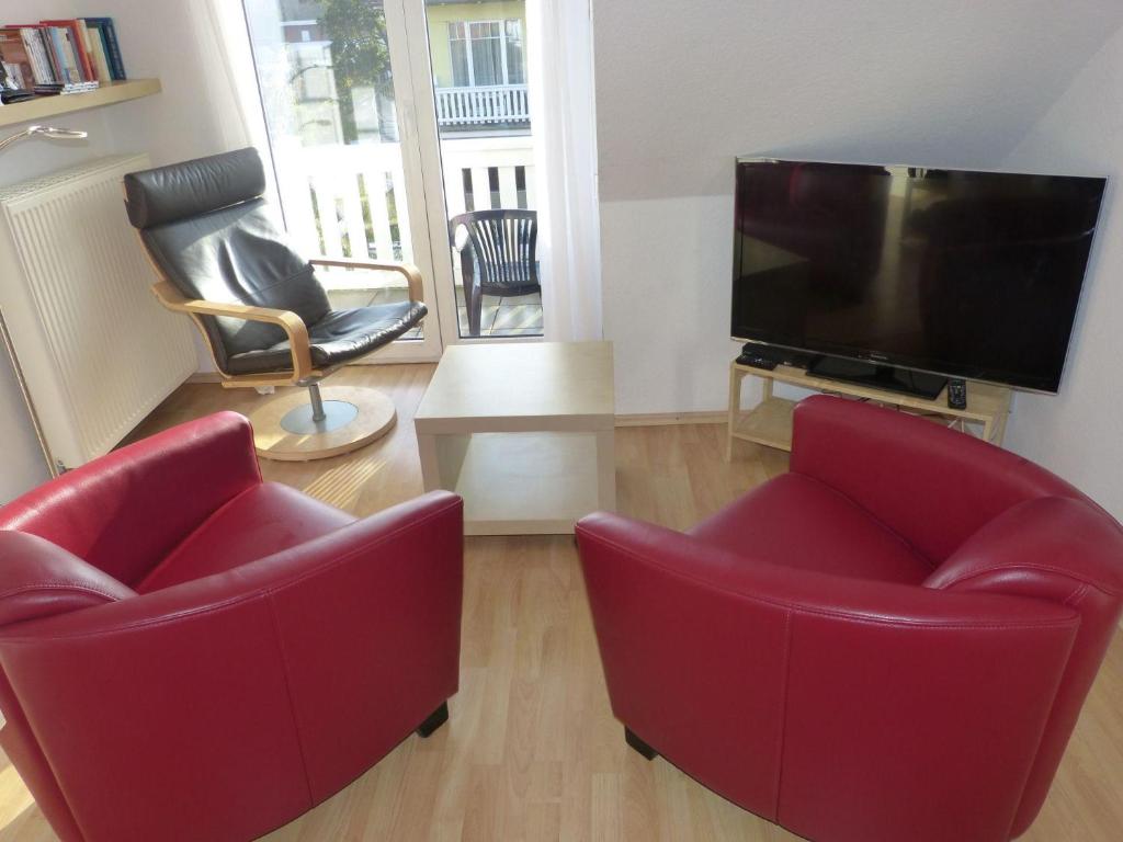 a living room with two red chairs and a flat screen tv at Strandschloesschen-Haus-II-WE-23-9743 in Kühlungsborn