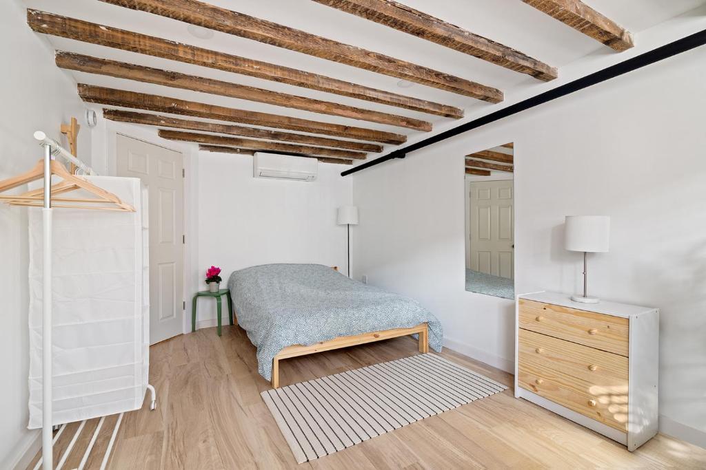 a bedroom with white walls and a bed and a dresser at Cozy, Large and Fully Furnished - Near the L Train in Brooklyn
