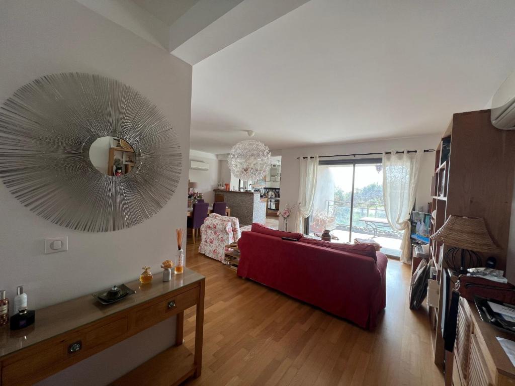 un salon avec un canapé rouge et un miroir dans l'établissement APPARTEMENT STANDING AJACCIO 5mn A PIEDS PLAGE DU RICANTO AJACCIO, à Ajaccio