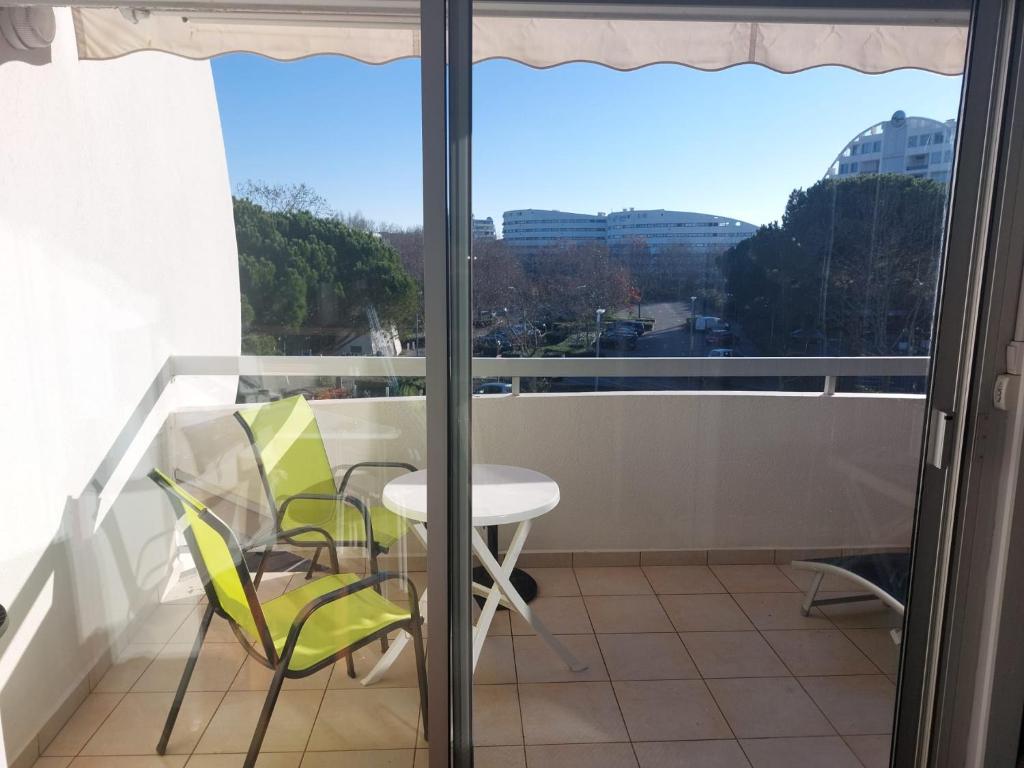 balcón con mesa, sillas y ventana en Joli studio avec piscine à 200m de la plage parking privé, en La Grande-Motte