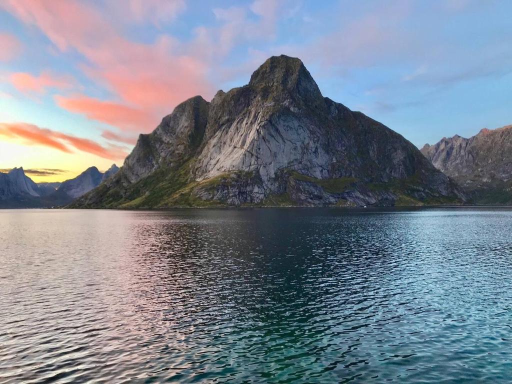 einen Berg inmitten eines Sees bei Sonnenuntergang in der Unterkunft Reinefjorden Lodge in Reine