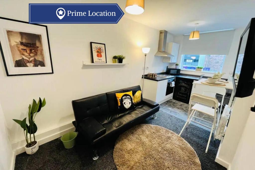 a living room with a black leather couch and a kitchen at Artistic 1Bed Apt near the City Centre in Liverpool