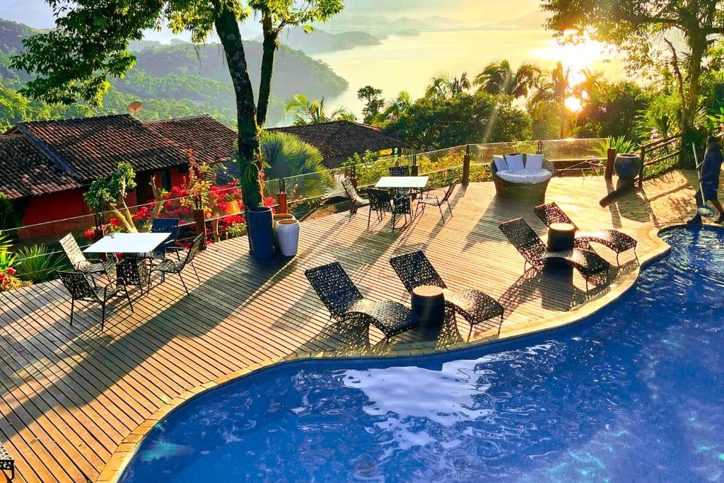 a deck with chairs and tables next to a swimming pool at Pousada Sonho Real in Angra dos Reis