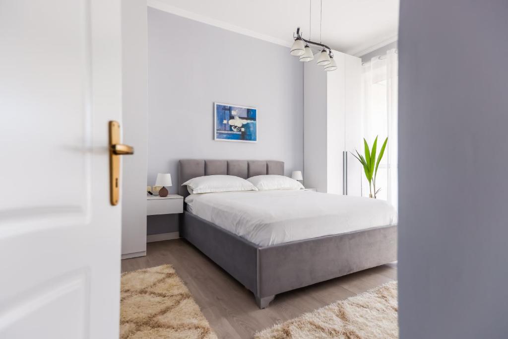 een witte slaapkamer met een bed en een raam bij Viewpoint Central apartment in Tirana