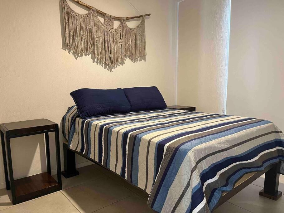 a bed with a blue and white striped blanket in a room at Departamento moderno en Guadalajara in Guadalajara