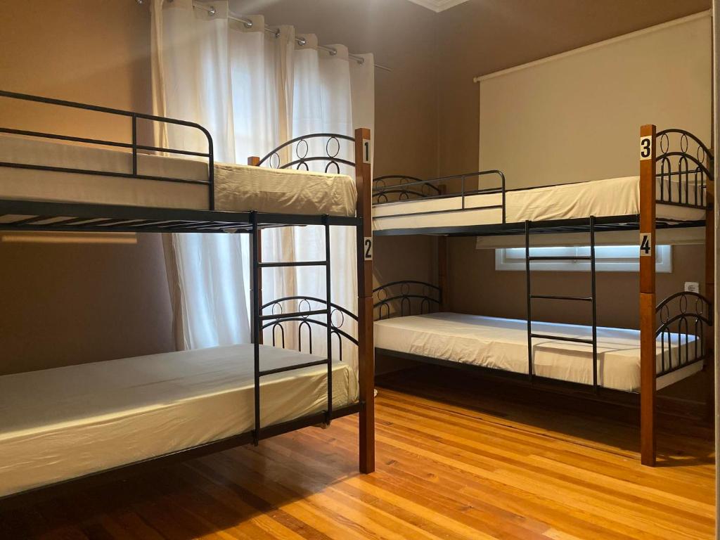 three bunk beds in a room with wooden floors at Lait Hostel in Ioannina