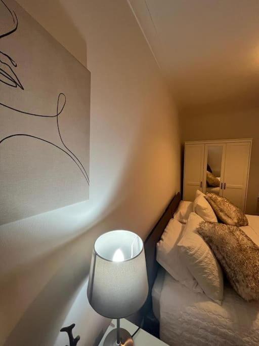 ein Schlafzimmer mit einem Bett und einem Tisch mit einer Lampe in der Unterkunft Albert House in Airdrie