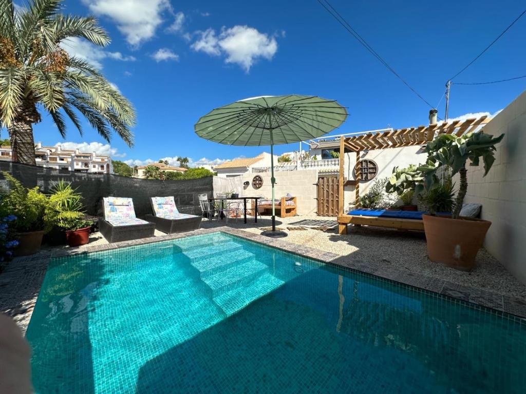 una piscina con ombrellone accanto a una casa di Casa Eline de Lujo Casco Antiguo Altea piscina privada y jardin ad Altea
