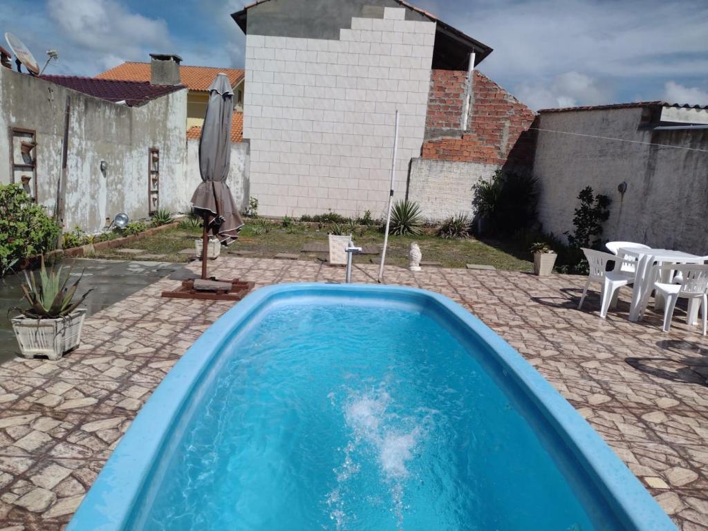 a swimming pool in a yard with a table and chairs at CASA COM PISCINA EM BALNEÁRIO PINHAL RS in Pinhal
