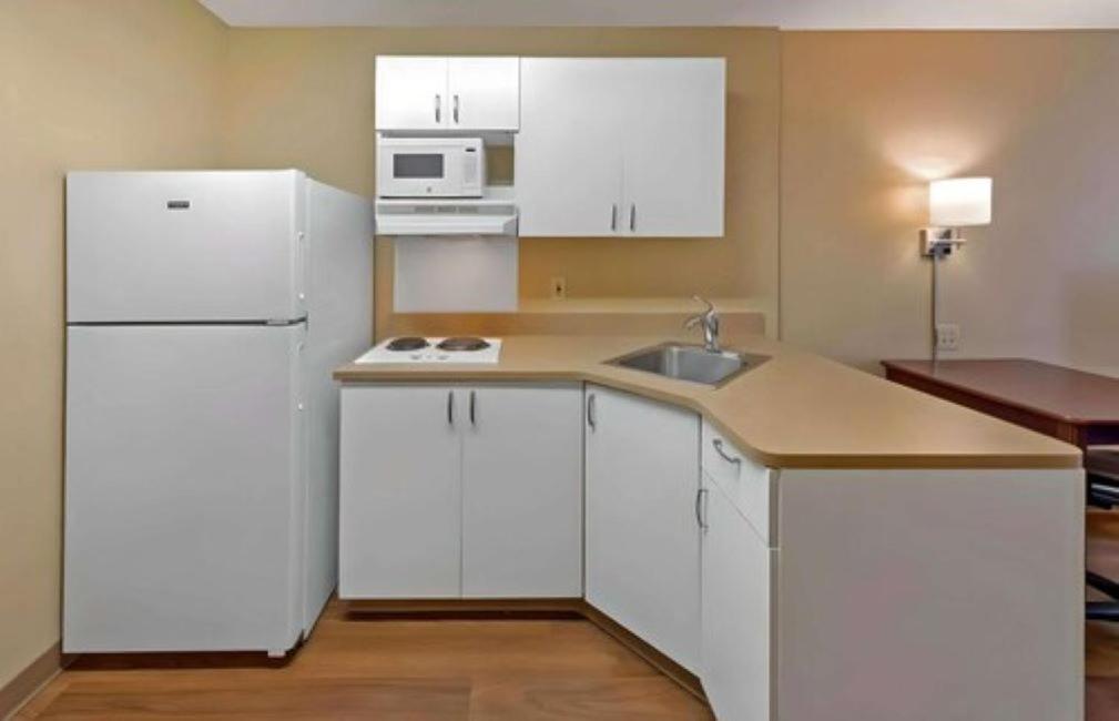 a kitchen with white cabinets and a white refrigerator at MainStay Suites Chicago Hillside in Hillside